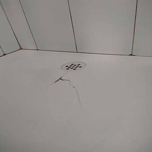 Cracked bathroom tile near drain, indicating potential repair needs.