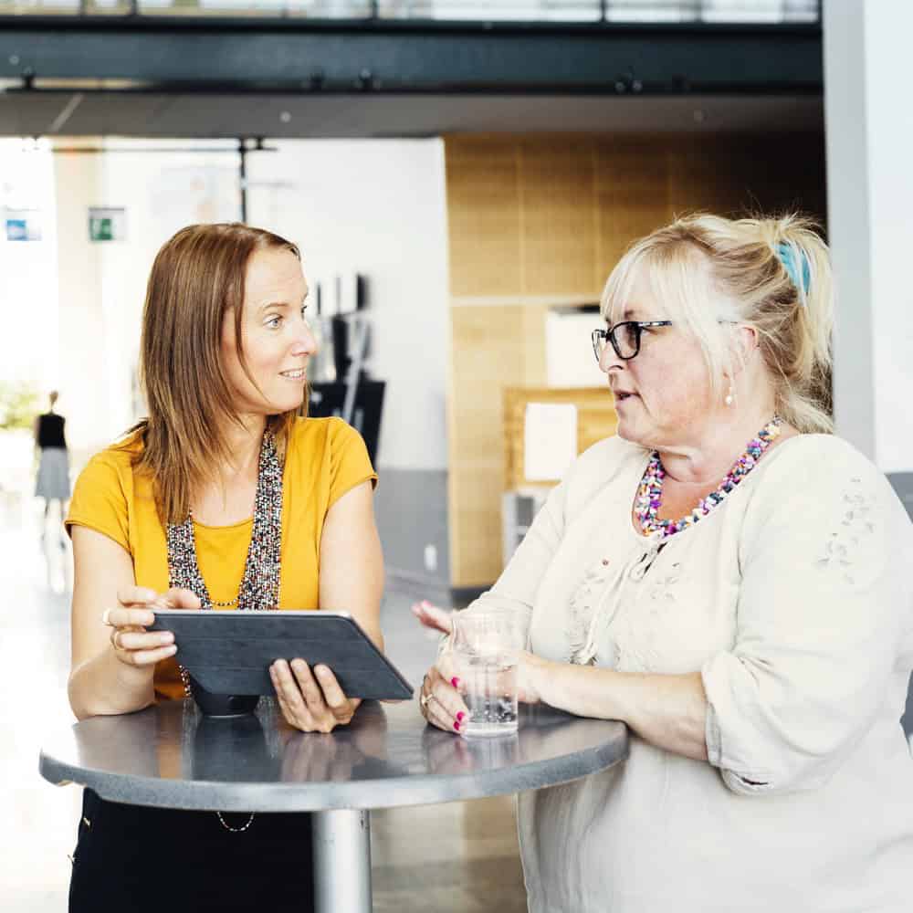 Two people in conversation, one recommending a business to the other as a referral.