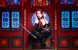 中華風の豪華な内装の部屋で、艶やかなチャイナドレスをまとい、鞭を手に堂々とポーズを決める女王様。BDSMの支配者としての威厳と官能を湛えた姿。