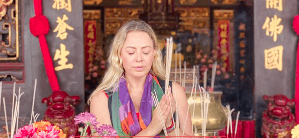Lámpara de incienso y mujer en ceremonia espiritual en un templo chino tradicional.