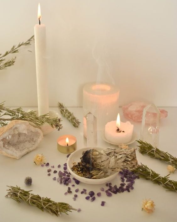 Vela encendida, cristales y plantas en altar de meditación, ambiente de paz y armonía.