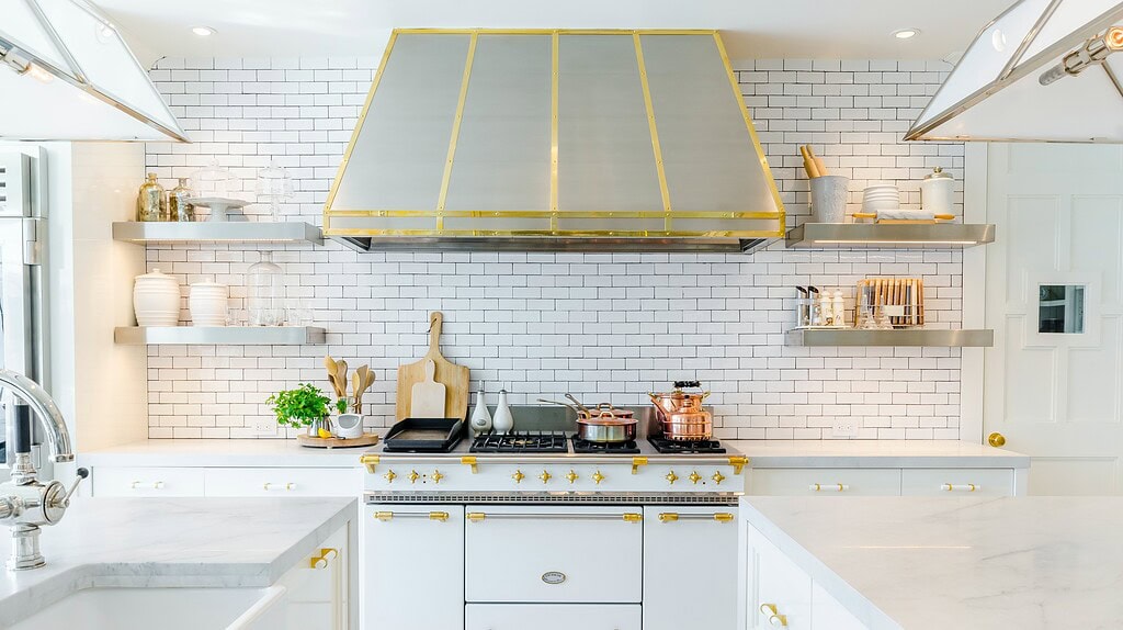 Cocina luminosa con campana extractora dorada y detalles en blanco y dorado.