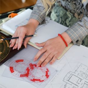 Persona analizando planos y diagramas en una mesa de trabajo.