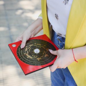 Persona sosteniendo un diagrama de Feng Shui en una mano, en un entorno exterior.