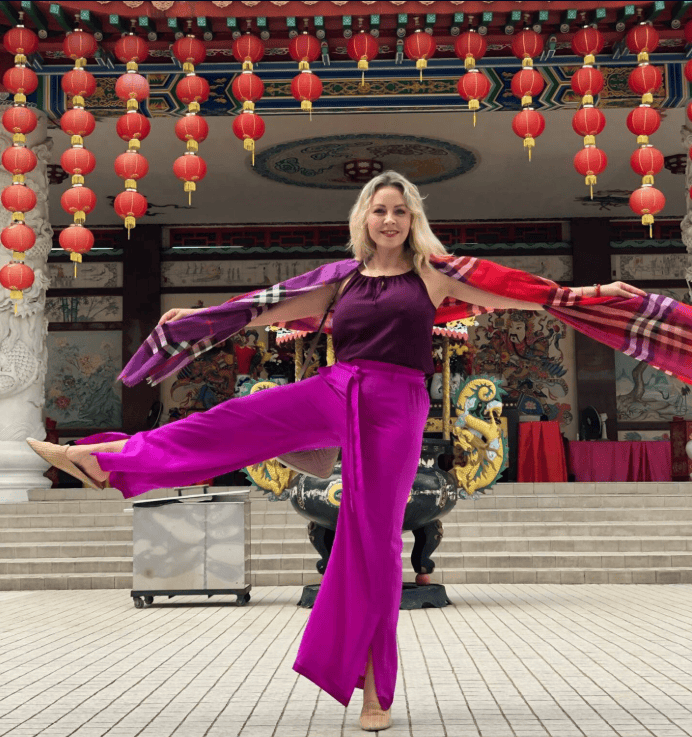 Mujer bailando en un templo con linternas rojas y decoración tradicional china.
