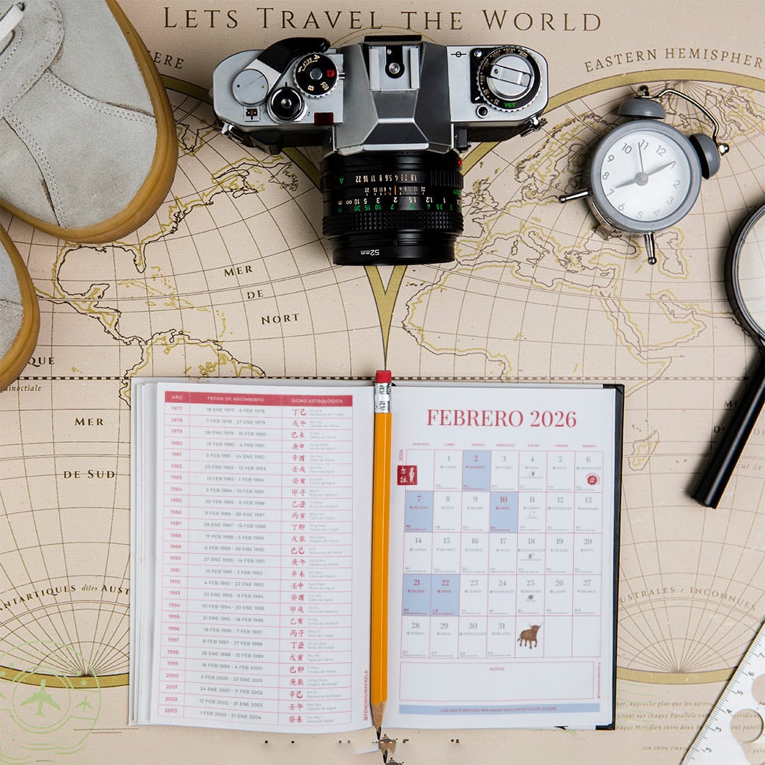 Guía de viaje con cámara, calendario y mapas en un escritorio de planificación.