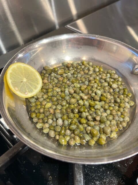 Picture of a small pan filled with capers and lemon. 