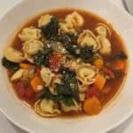Picture of a white bowl filled with tortellini vegetable soup.