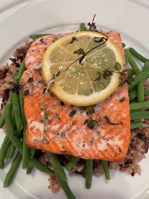 Picture of Grilled Wild Sockeye Salmon with Lemon & Thyme sitting on a bead of wild rice and green beans.