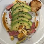 A plate with tuna steak, avocado and Hawaiian cabbage Salad on it.