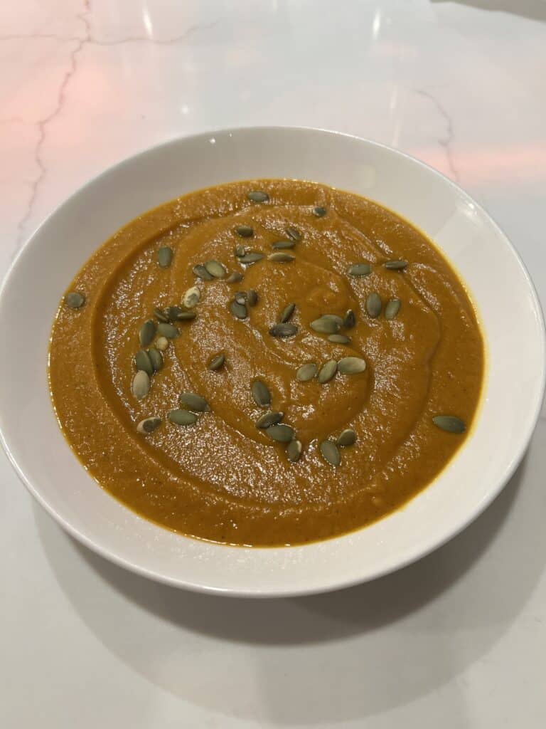 Picture of a bowl of creamy butternut squash soup topped with pumpkin seeds.