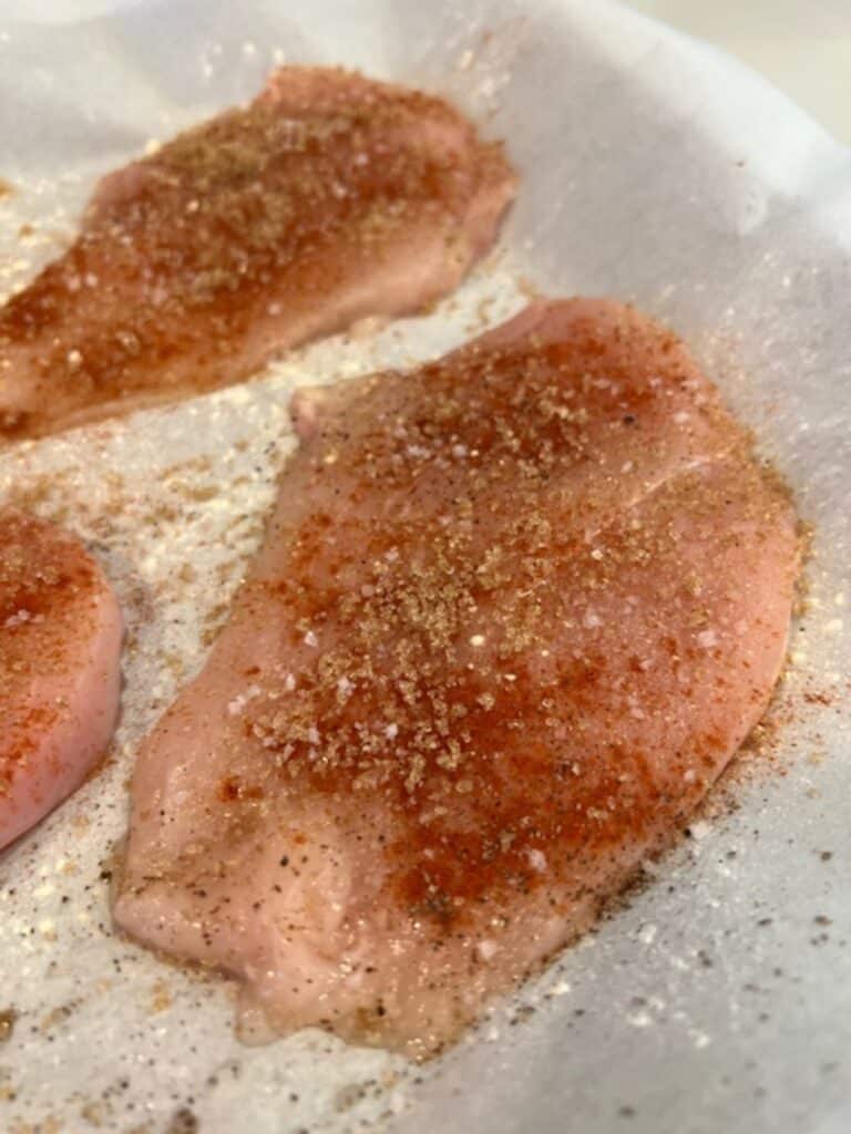 Picture of raw sweet and savory chicken breasts on a sheet pan.