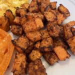 Picture of Lily's Spiced Sweet Potatoes on a plate paired with heirloom tomatoes and farm fresh eggs.