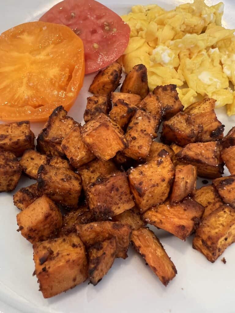 Picture of Lily's Spiced Sweet Potatoes on a plate paired with heirloom tomatoes and farm fresh eggs.