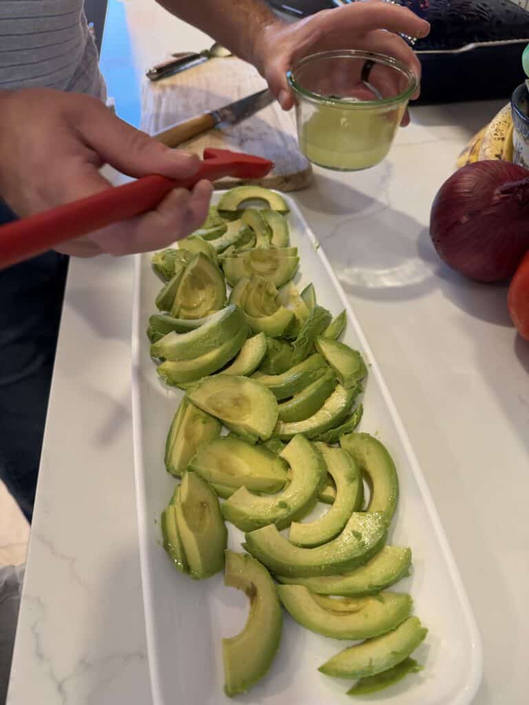 Picture of sliced avocado on a long plate painted with lime juice. 