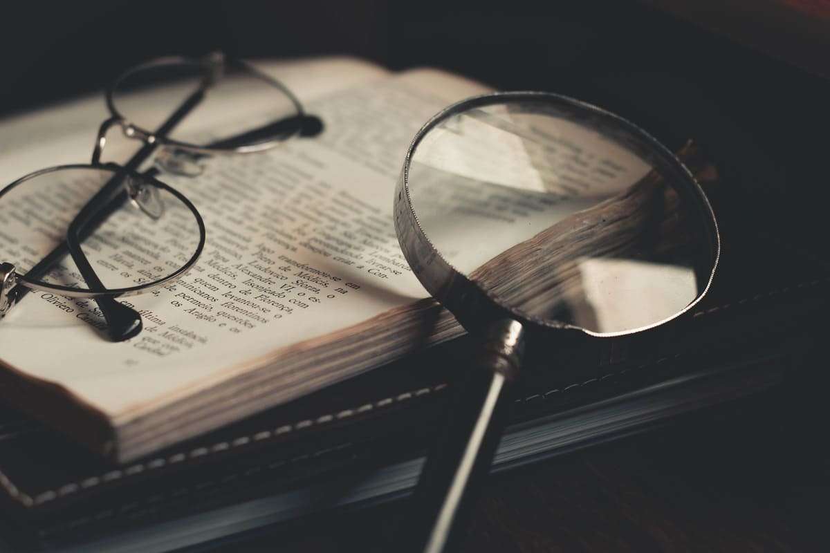 Óculos y lupa sobre libro de filosofía abierto.