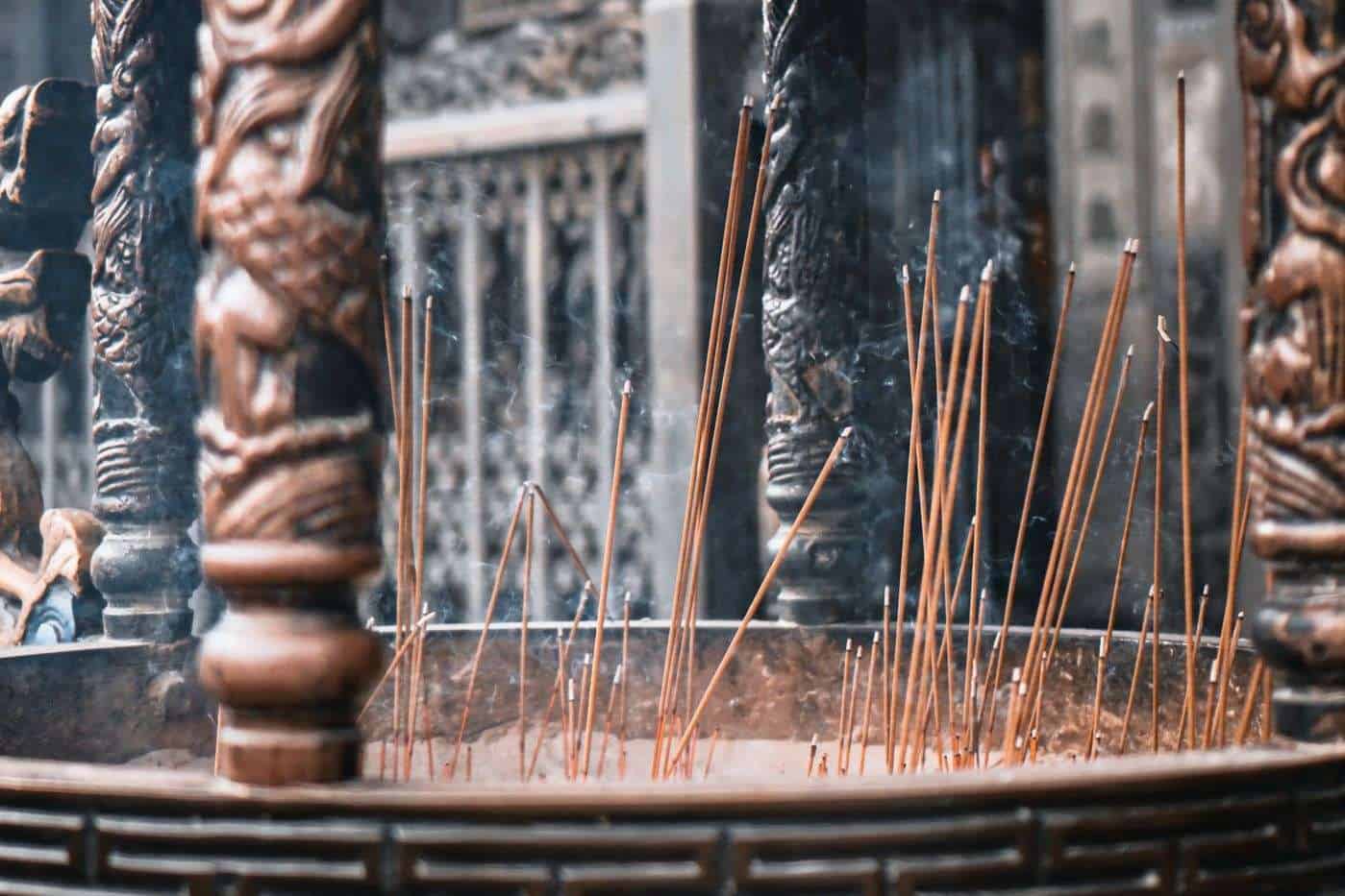 Varitas de incienso en un altar con detalles en madera y metal, en un ambiente de ceremonia o ritual.