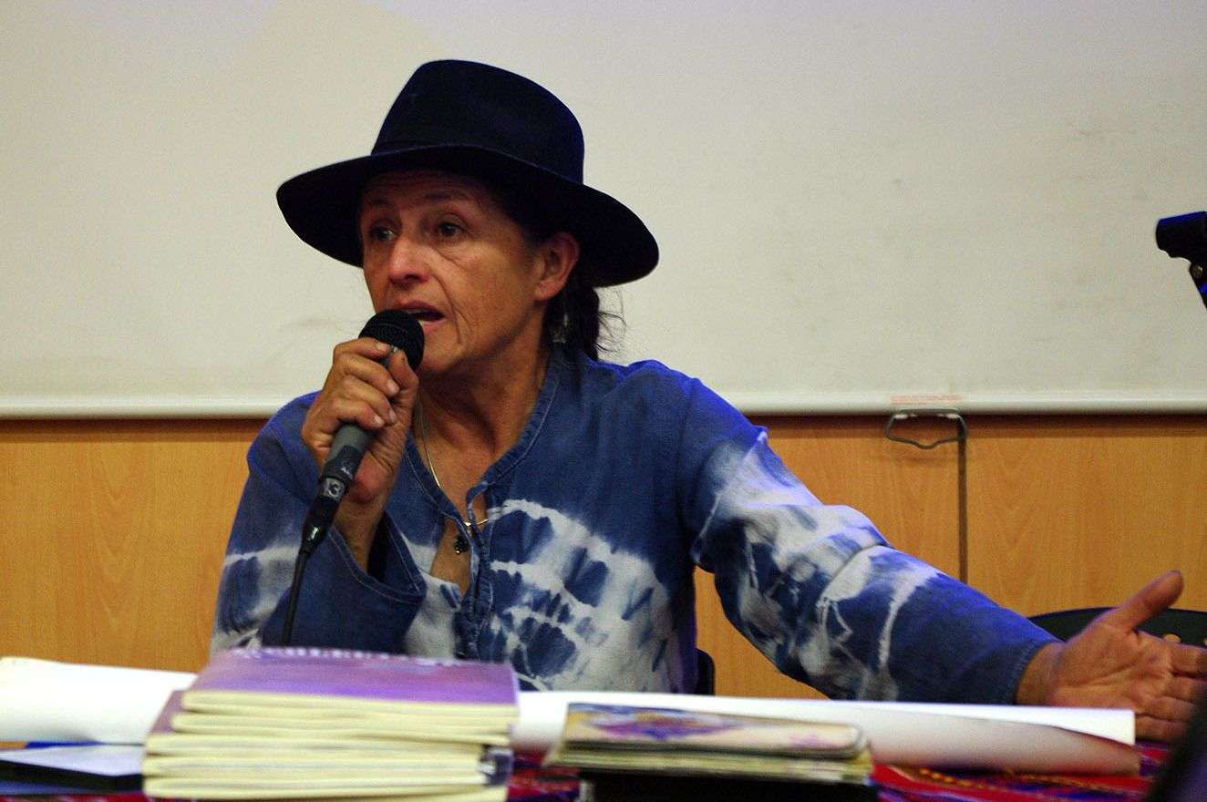 Pensadora con sombrero negro hablando en conferencia o seminario.