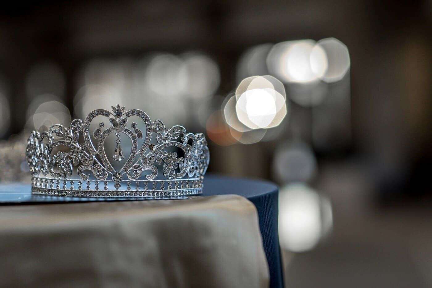 Brillo de una tiara de plata con pedrería en un fondo borroso.