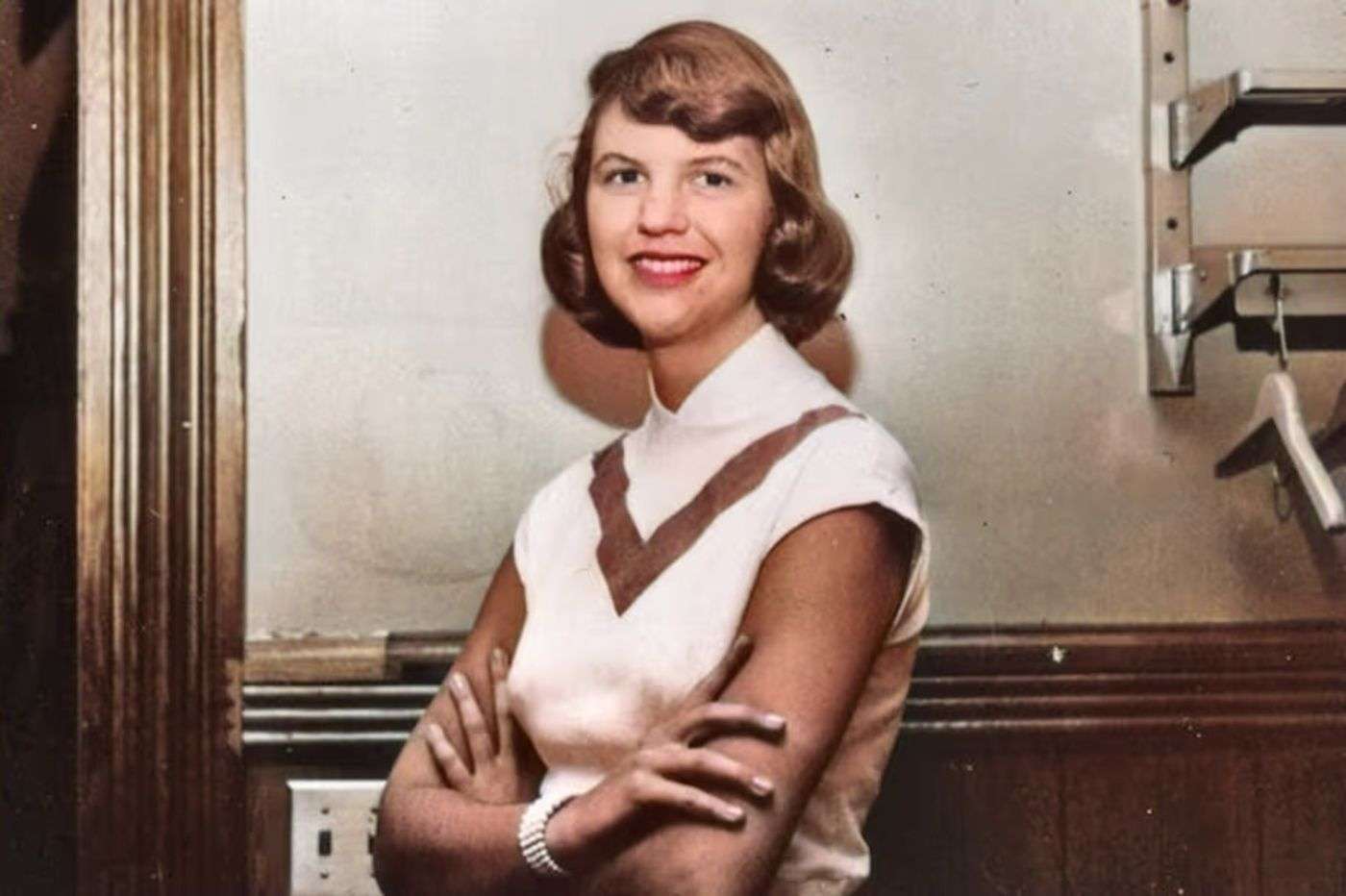 Joven mujer sonriendo con brazos cruzados, estilo vintage.
