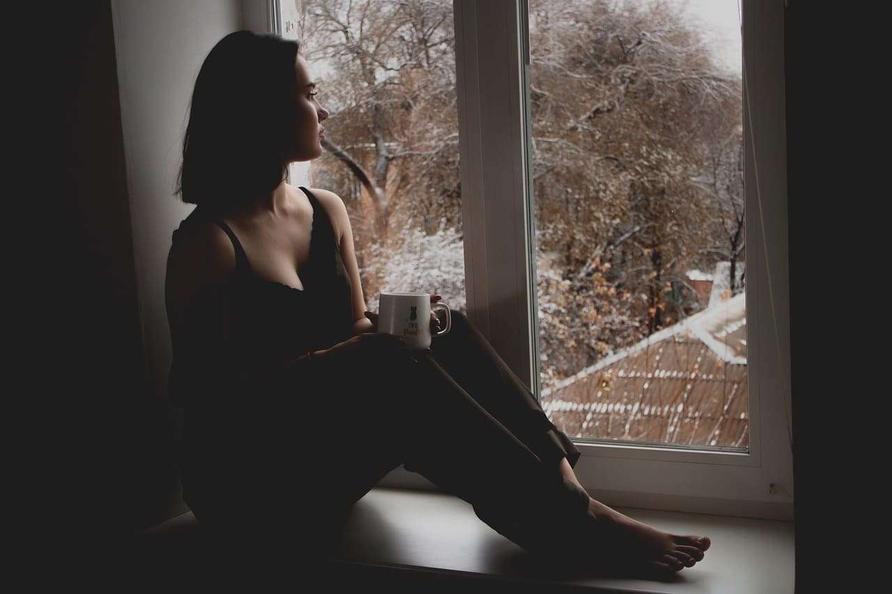 Reflexión femenina en ventana, mujer con taza, paisaje invernal, introspección, filosofía en la red.