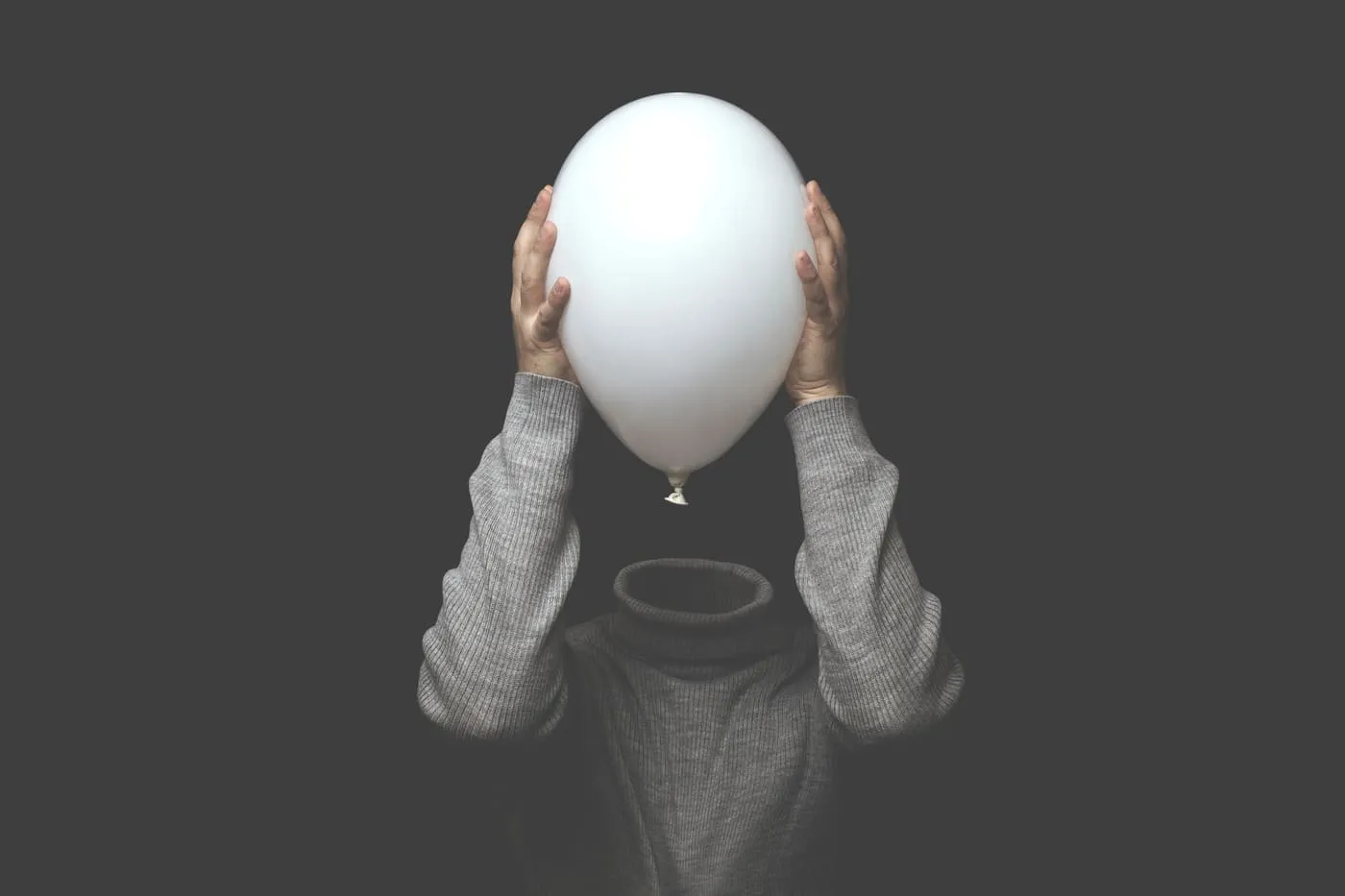 Boli de helio enmascarado con un cuerpo humano y manos sobre el globo.