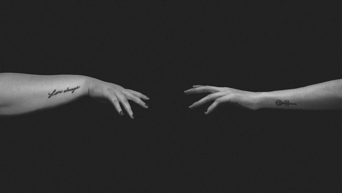 Manos entrelazadas en un fondo oscuro, simbolizando conexión y reflexión filosófica.