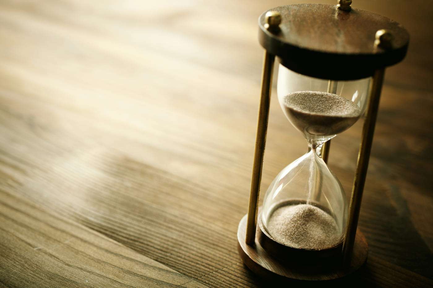 Reloj de arena de madera y cristal en superficie de madera natural.