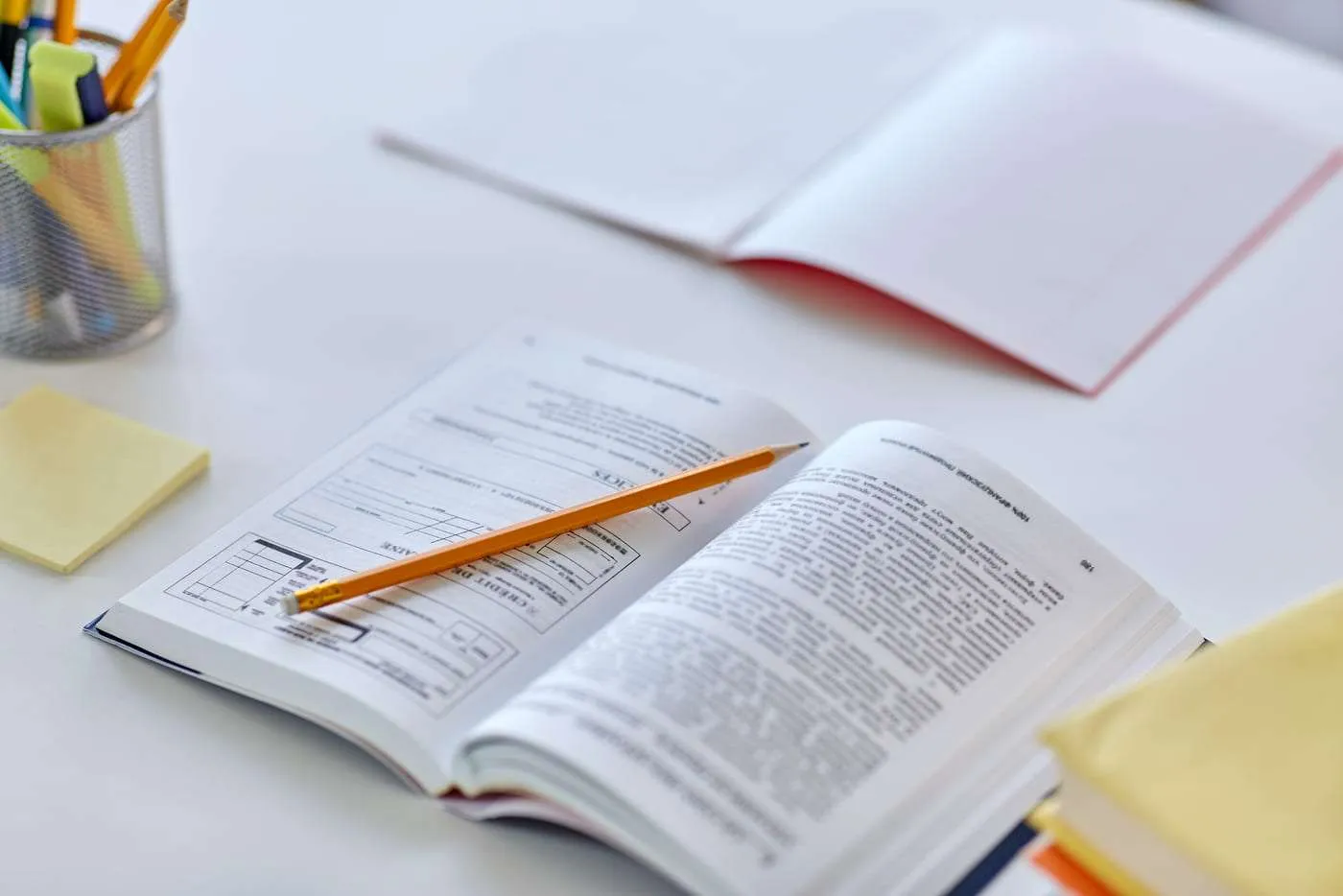 Libros y cuadernos de estudio con pluma y notas en mesa de trabajo.