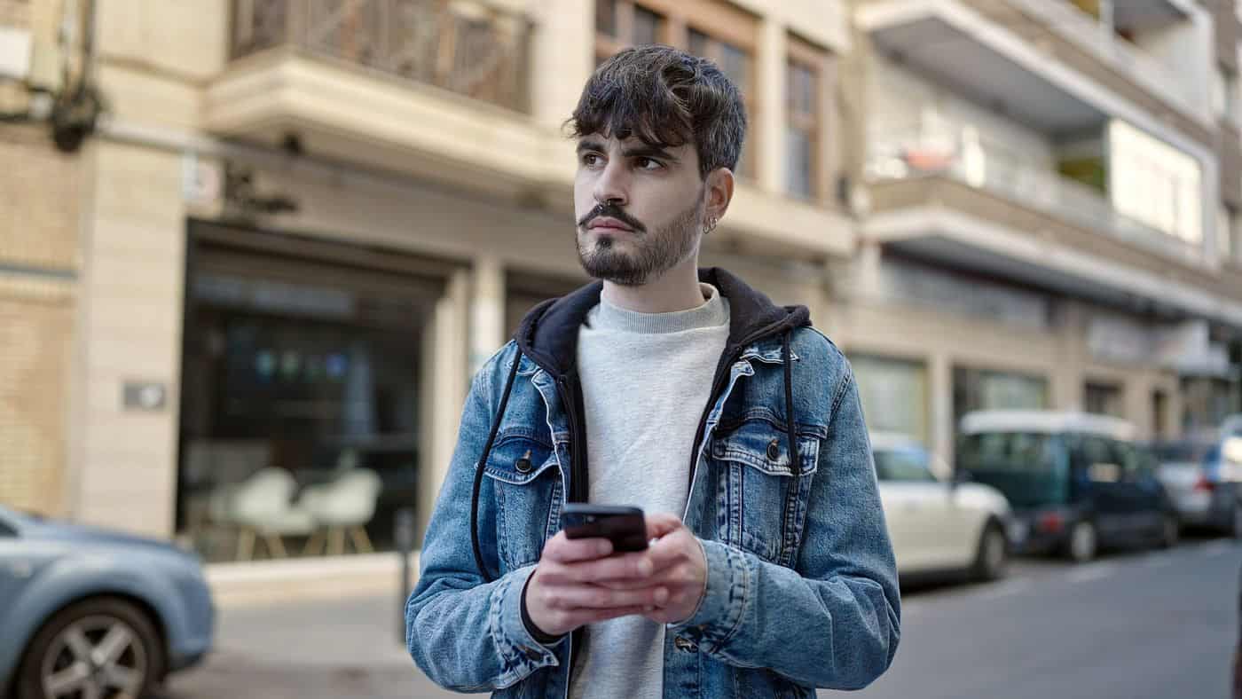 Joven hombre usando móvil en la calle, filosofía en la vida diaria.
