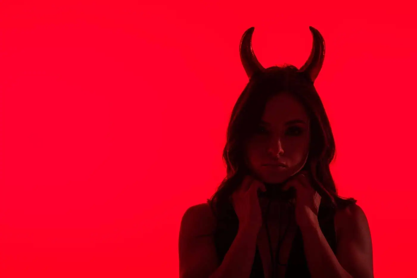 Imagen de mujer con cuernos, en tono rojo intenso, evocando simbolismo mitológico o temático.
