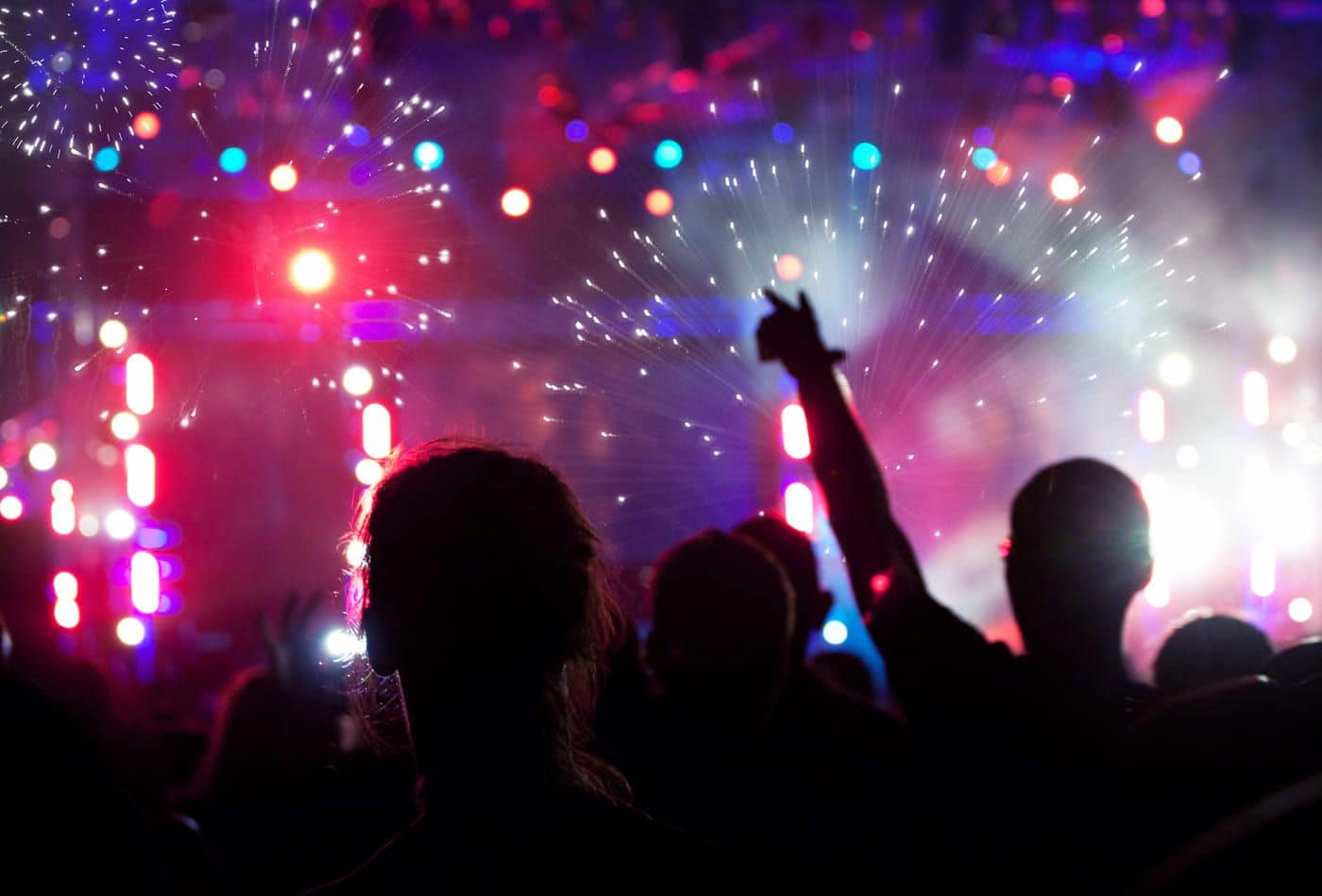 Ardiente fiesta con luces de colores y gente disfrutando en un concierto nocturno.