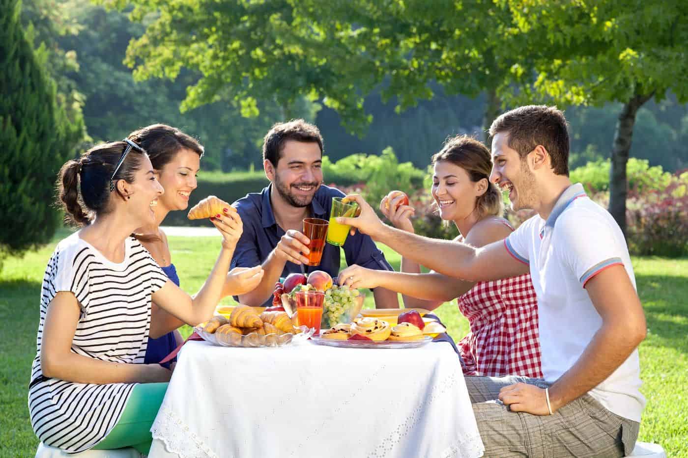 Sabores y risas en una comida al aire libre con amigos en un hermoso parque.