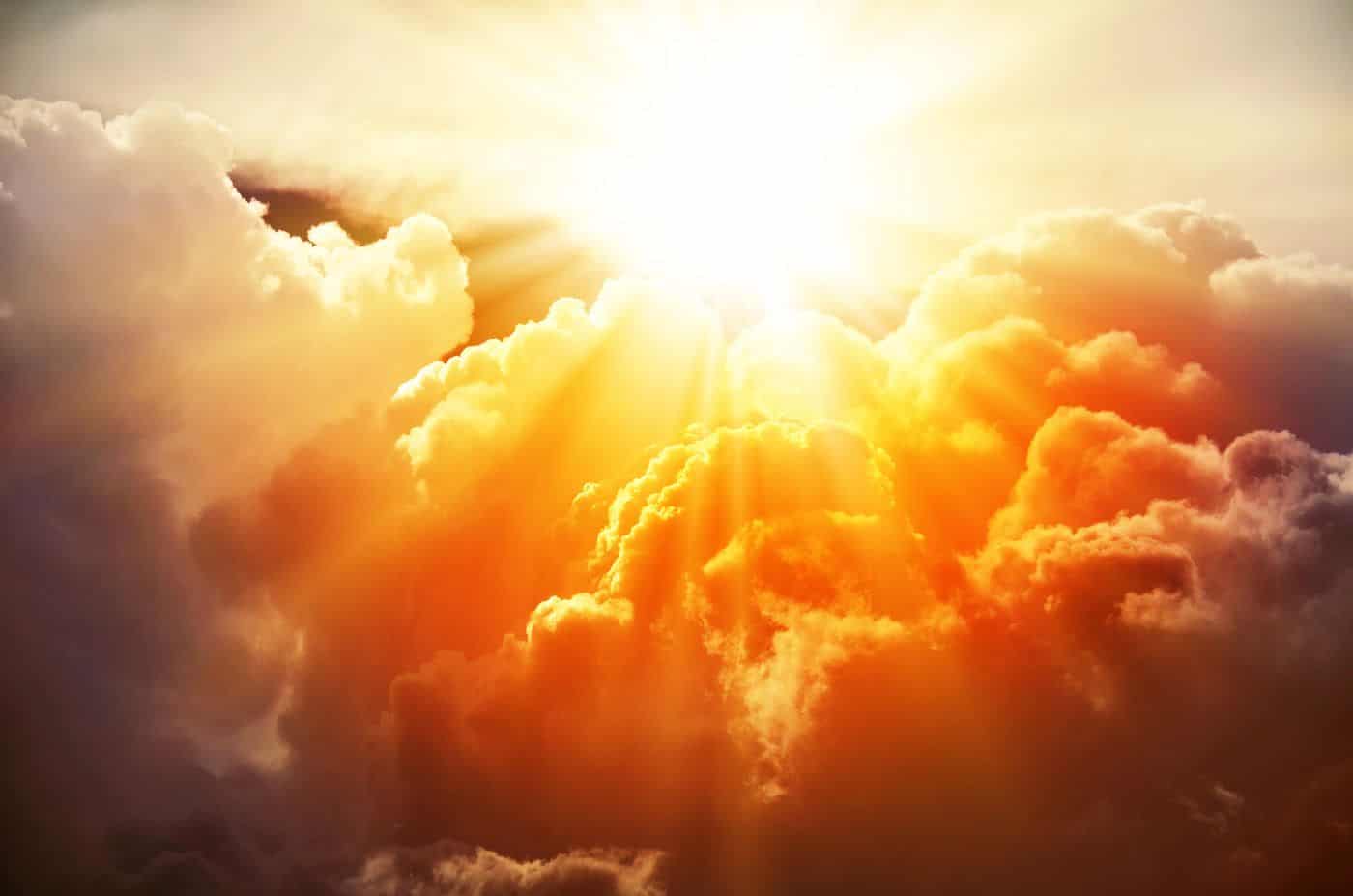 Luz solar brillante atravesando nubes doradas en un cielo celestial.