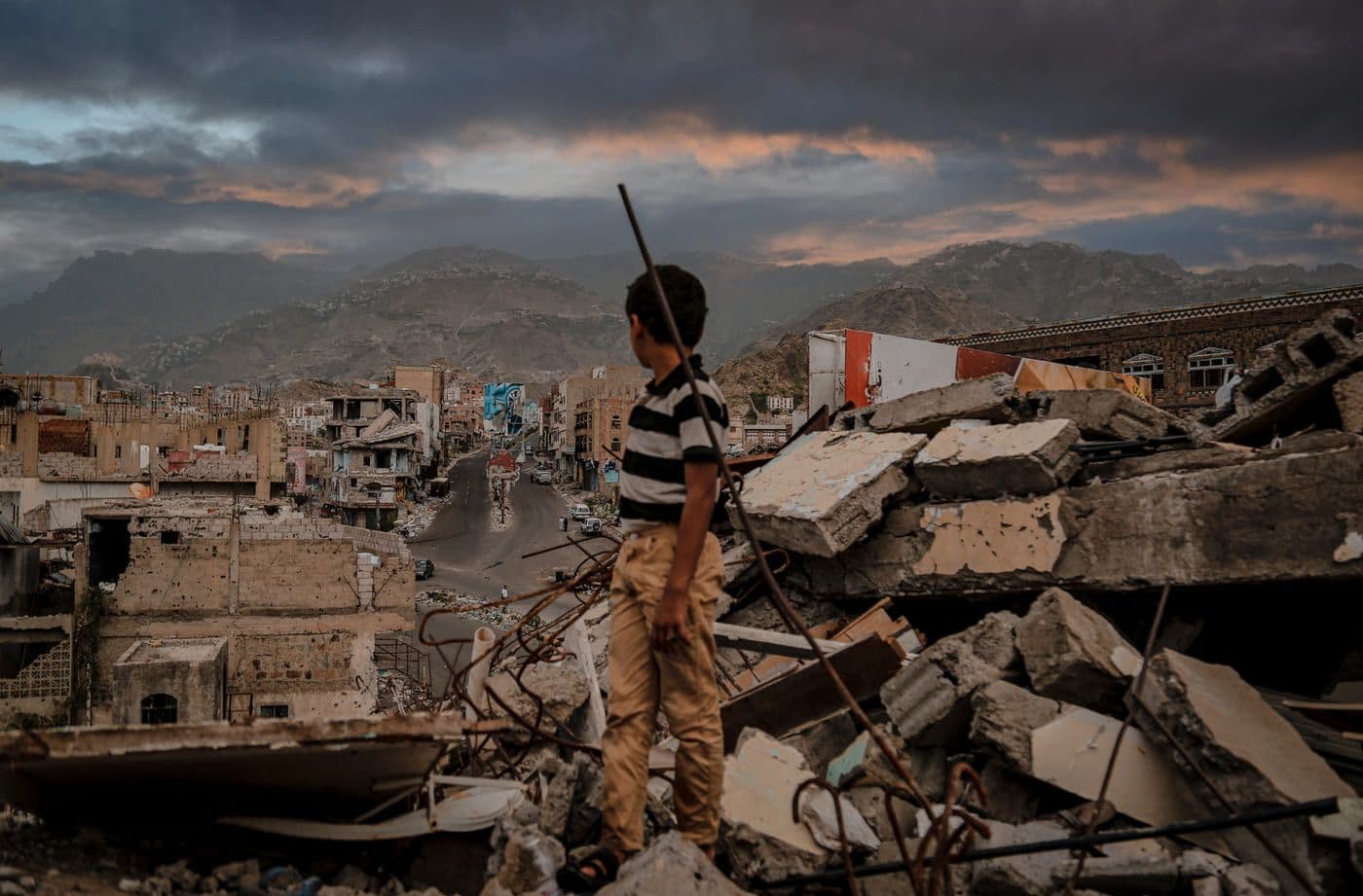 Damián centro histórico en ruinas tras desastre natural niño explorando escombros en ciudad destruida, paisaje urbano en destrucción, expresión de resiliencia y esperanza.