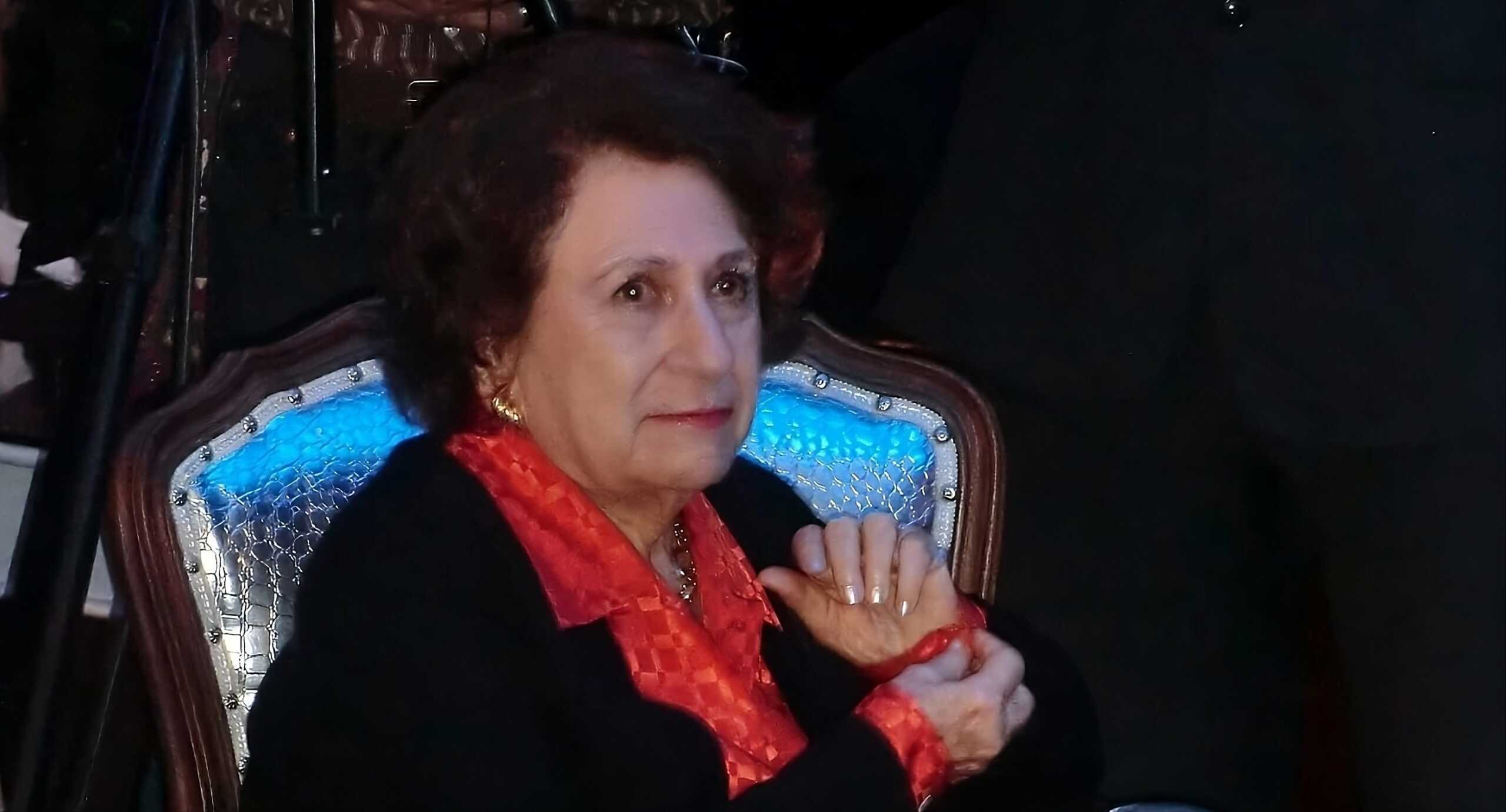 Profunda mujer mayor en un ambiente filosófico, sentada en una silla con expresión reflexiva y elegante.