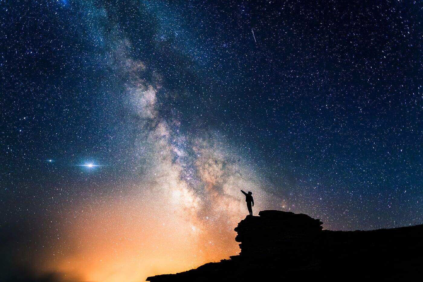 Espectacular cielo estrellado con la galaxia y una persona observando la inmensidad del universo.