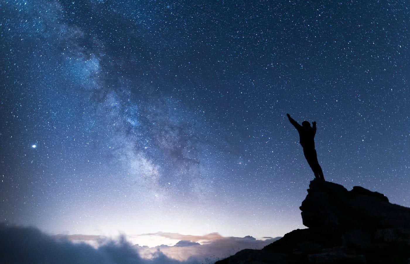 Estatua bajo cielo estrellado y la Vía Láctea, representando búsqueda de conocimiento y reflexión filosófica.