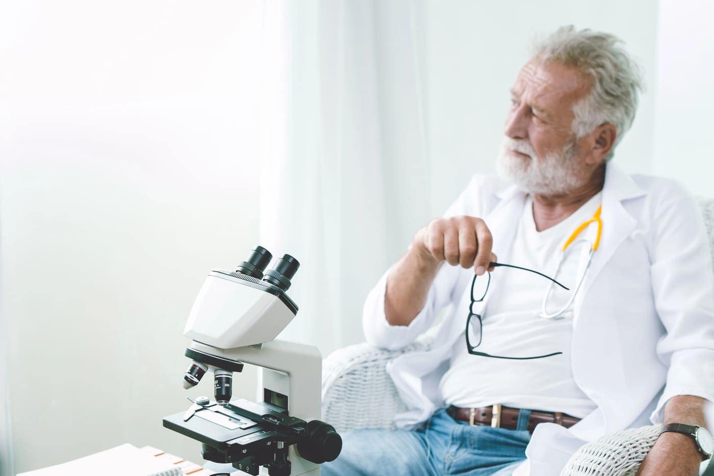 Señor científico con microscopio en un ambiente bien iluminado y tranquilo.