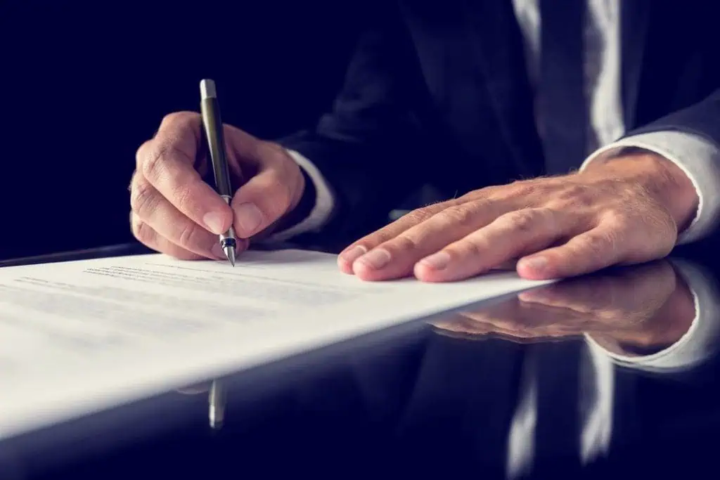 Escritor o filósofo firmando un documento, reflejando reflexión, conocimiento y divulgación filosófica.