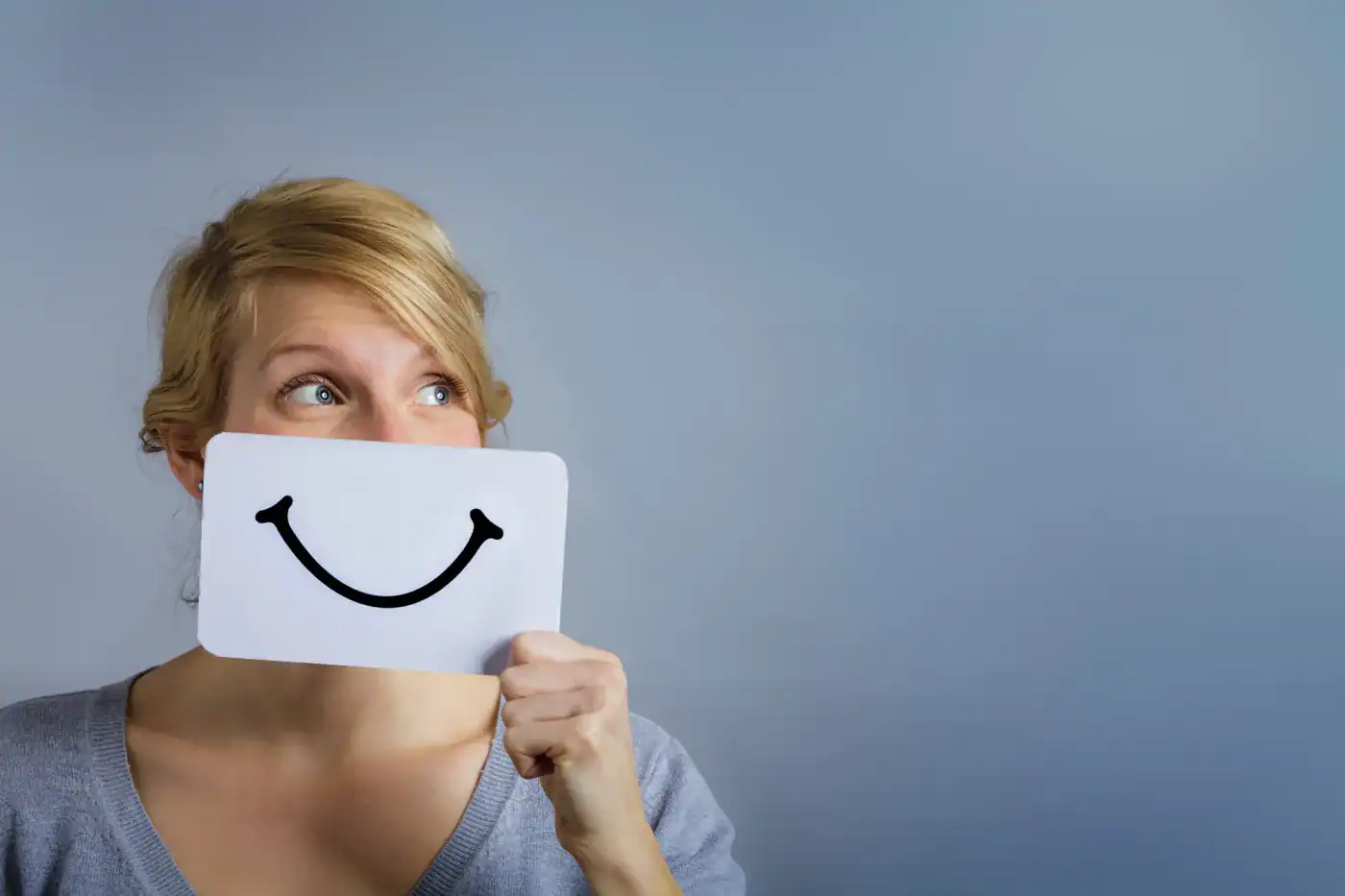 Sonriente mujer con máscara de sonrisa, imagen que representa la felicidad y el optimismo en filosofía.