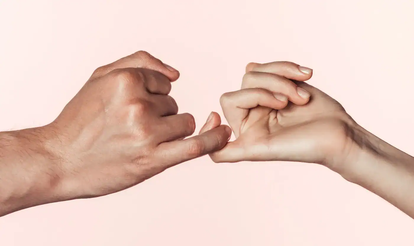 Dedos entrelazados que forman un corazón, simbolizando unión y amistad.