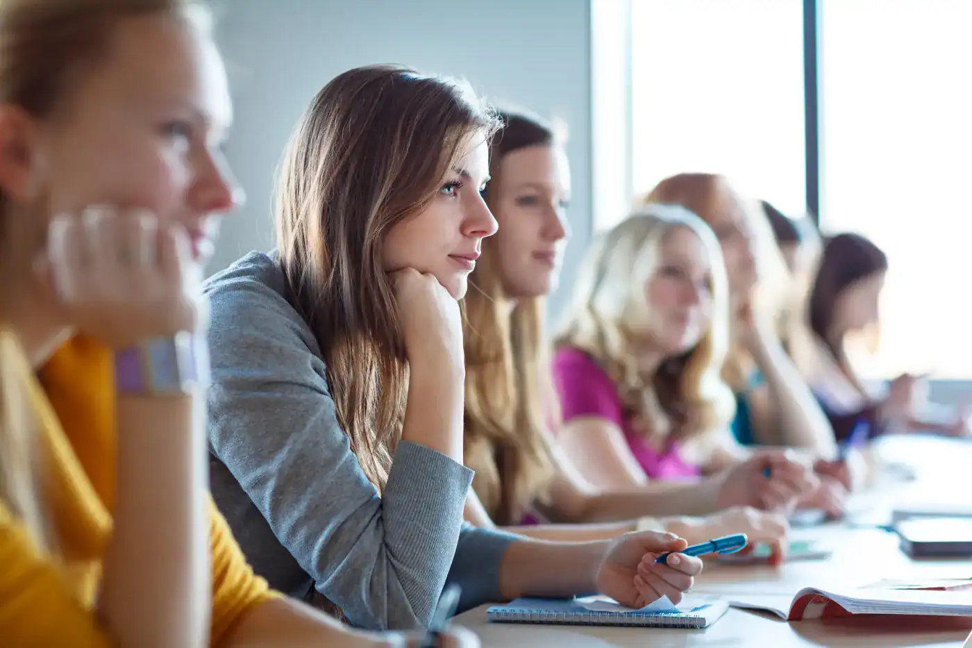 Estudiantes en una clase, atentos y concentrados, en una sala moderna y luminosa.