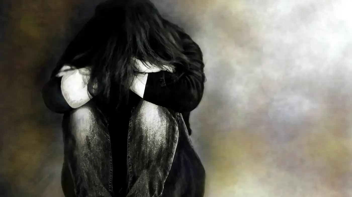 A woman with long hair sitting on the ground.
