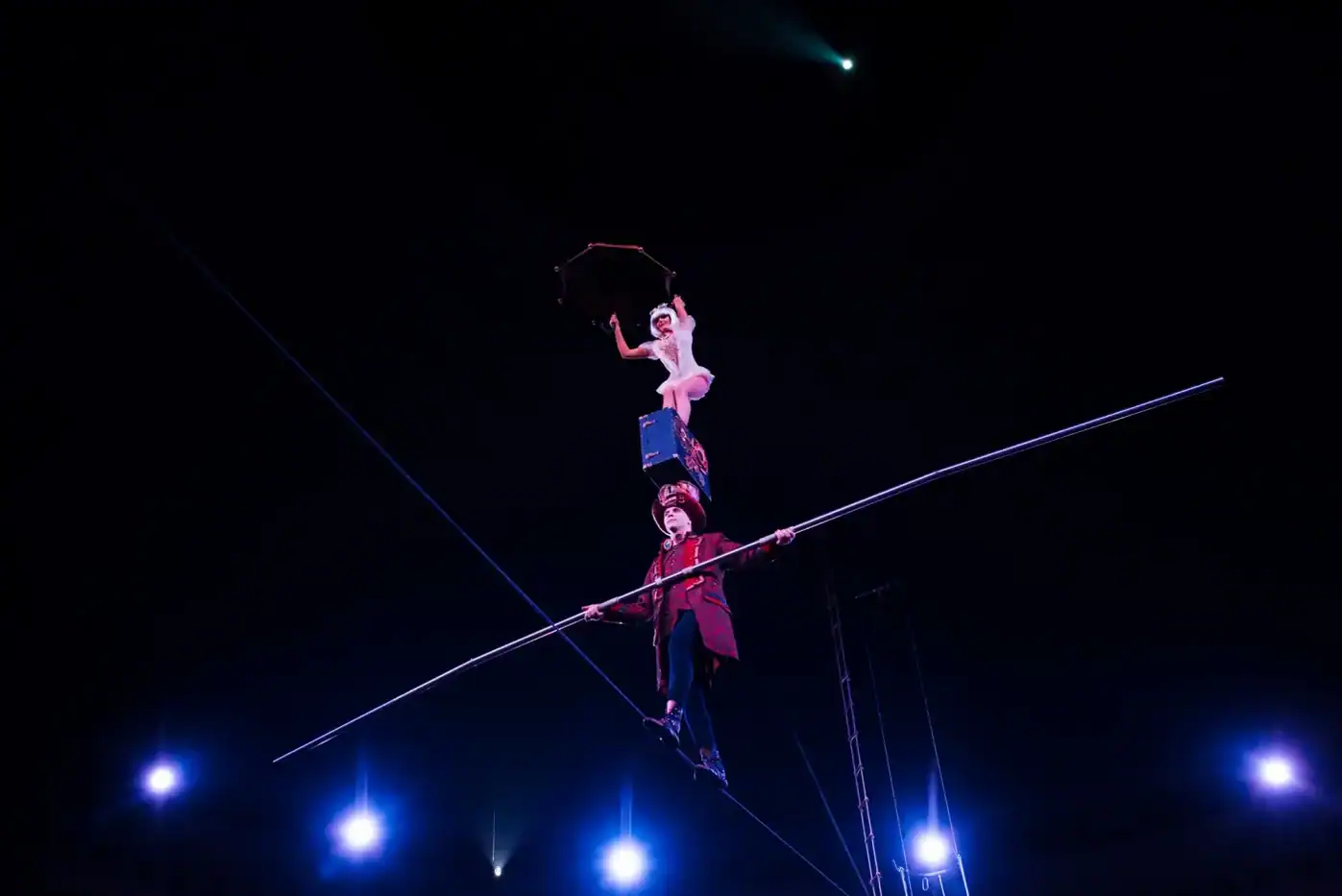 Espectáculo de circo en la noche con acróbatas y artistas en equilibrio en el aire.