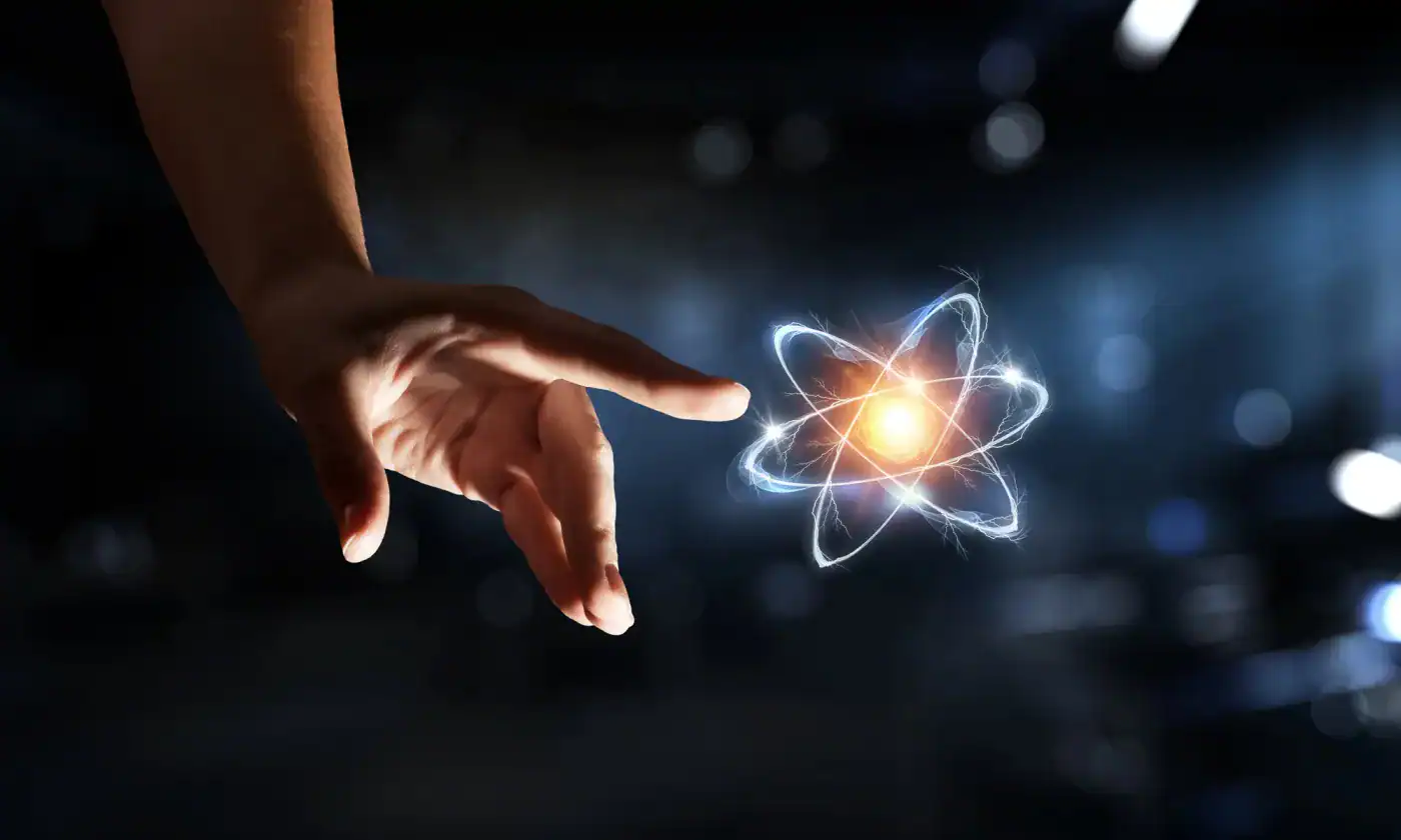 Innovadora mano alcanzando núcleo atómico con efectos de energía y luz en fondo oscuro.