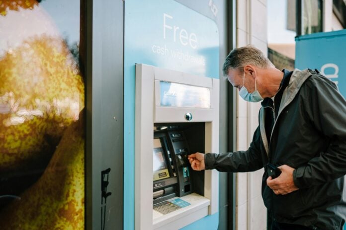 Man Using ATM Machine traditional bank