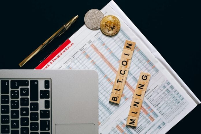 Top view of a laptop, Bitcoin coins, and financial indicators symbolizing Bitcoin mining and investm