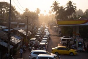 Long queue of vehicles and motorbikes at a fuel station in a dense tropical city