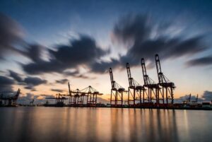 Wide view of a container port at dusk with cranes idle